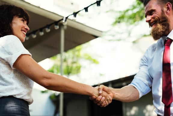 Man and woman shaking hands and smiling.