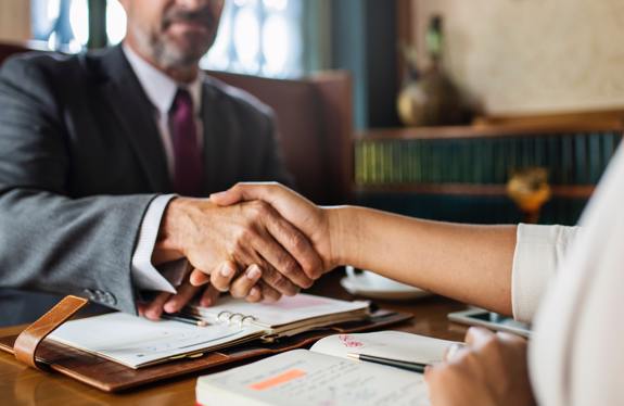 Man and woman shaking hands in restaurant booth. 