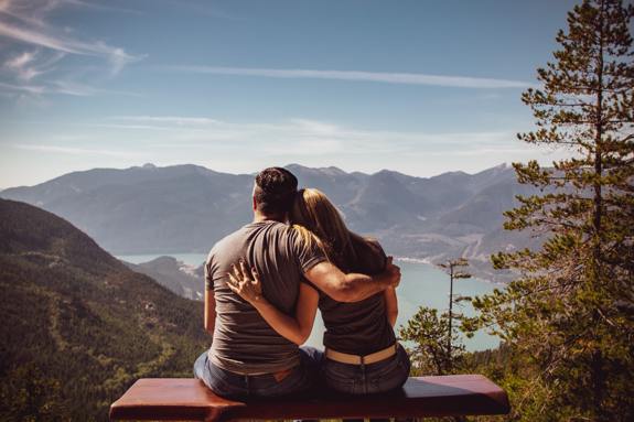Couple sitting on a bench overlooking a scenic lake.