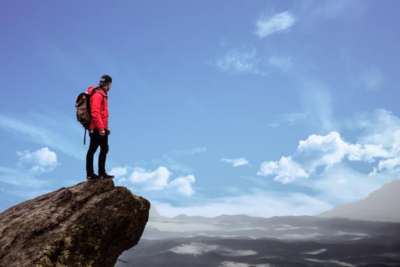 Man overlooking view from edge of cliff.