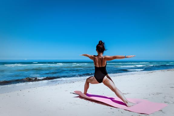 Woman doing yoga on the beach. 